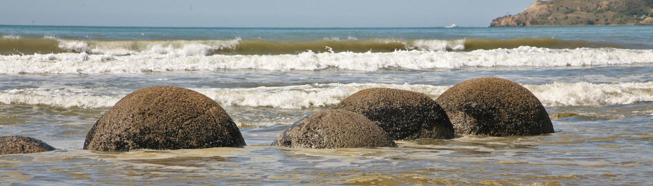 Runde Steine am Strand mit Wellen dahinter